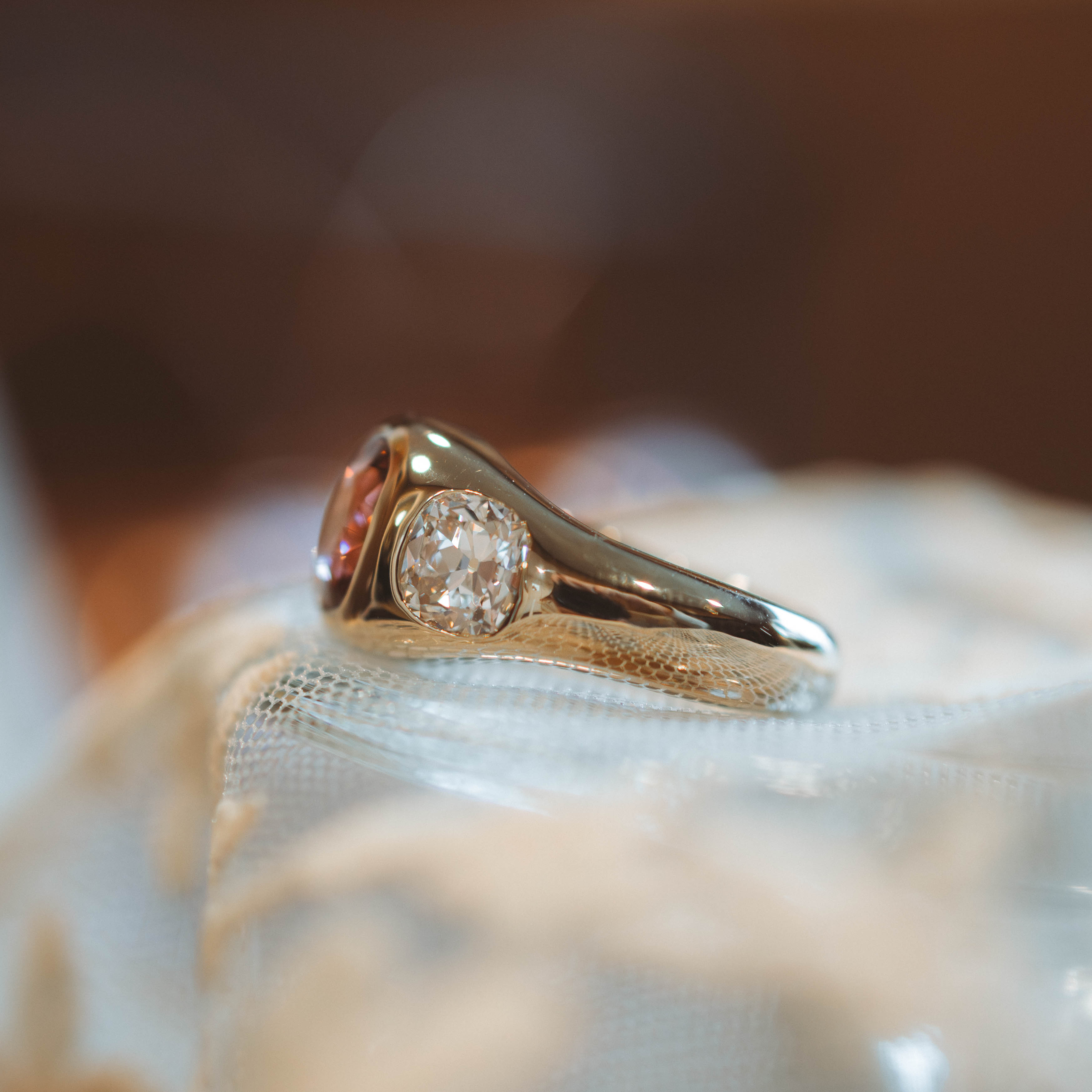 Gold ring with a diamond on a soft, blurred background, profile view