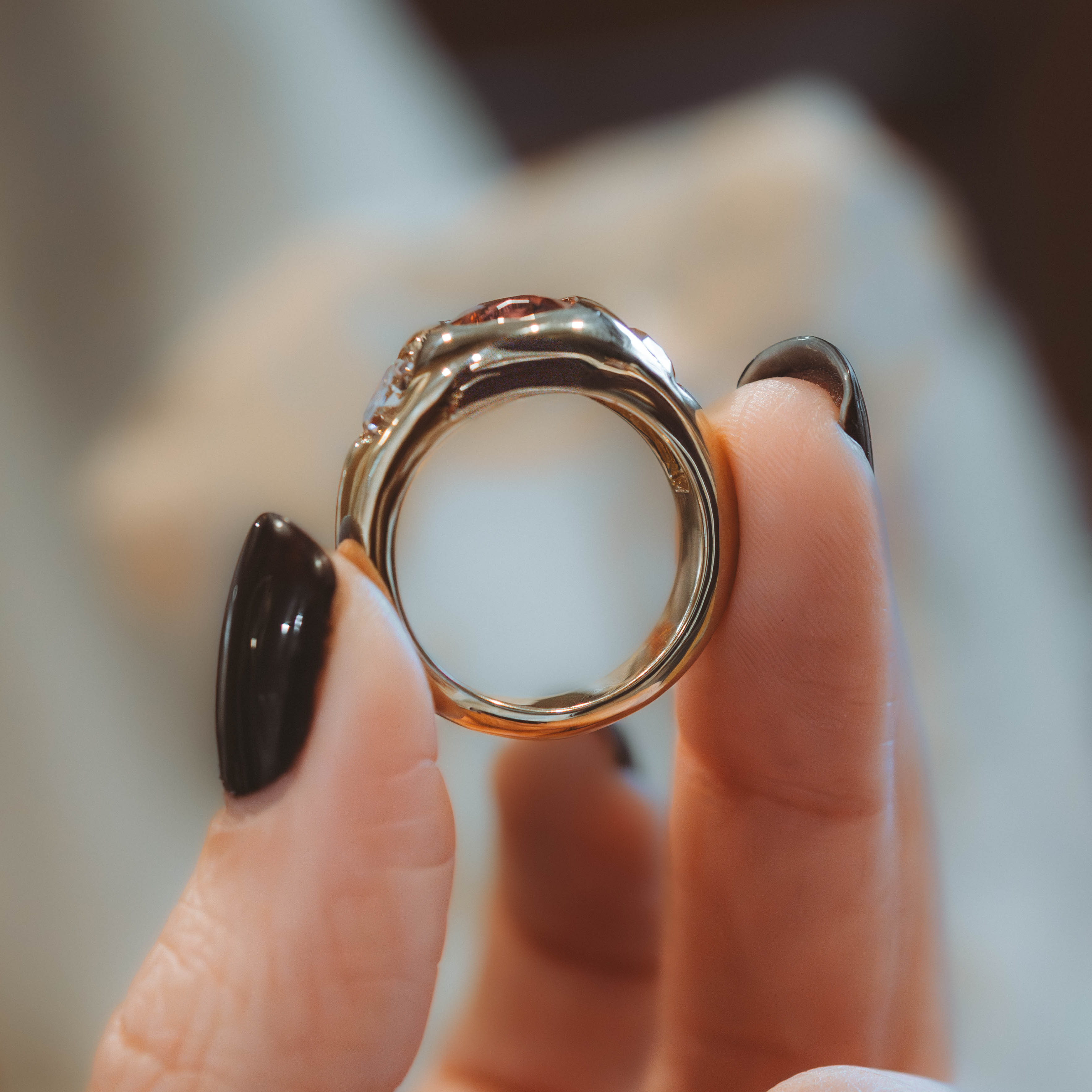 Close-up of a hand holding a decorative ring with a blurred background