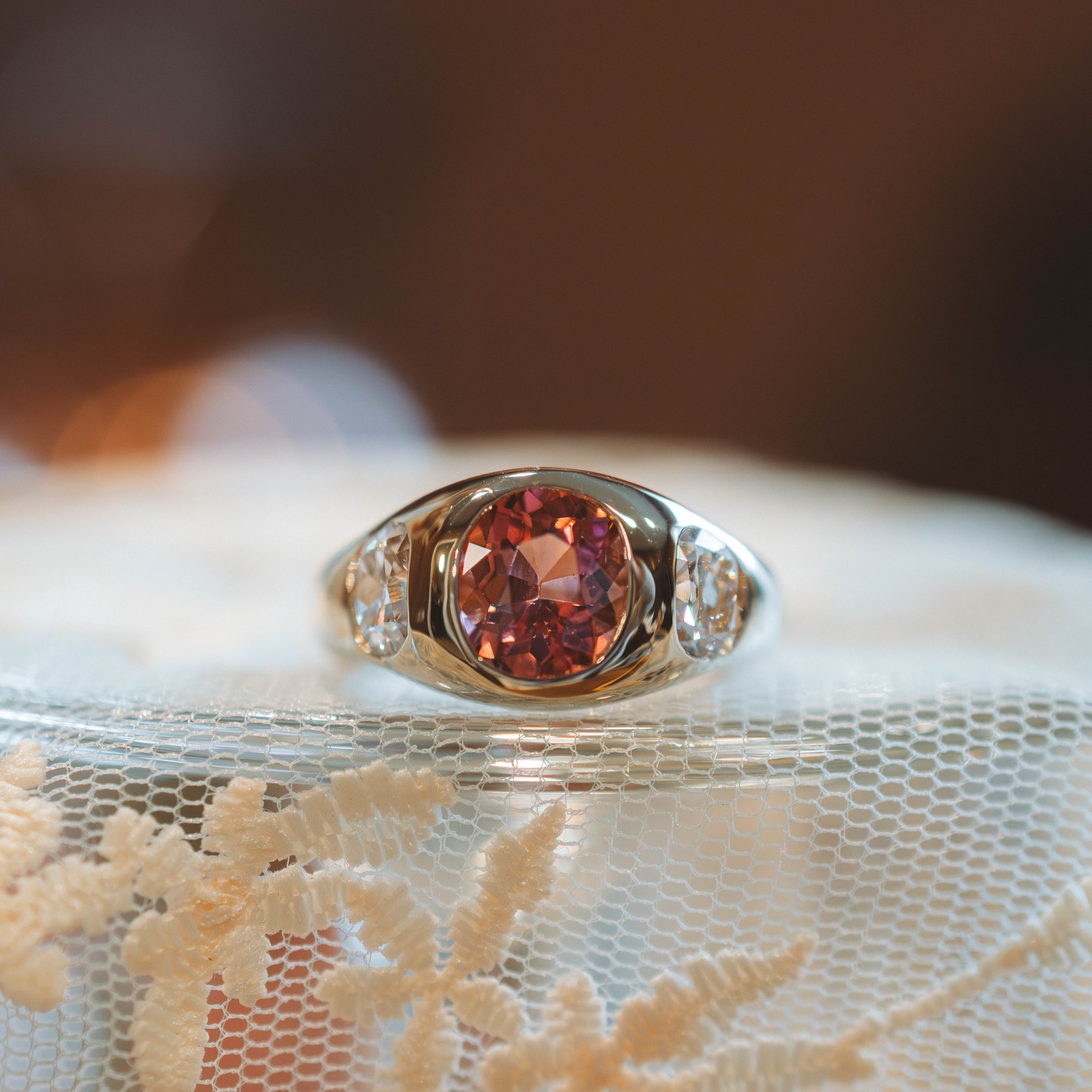 Gold ring with a tourmaline gemstone and diamonds on a lace fabric background