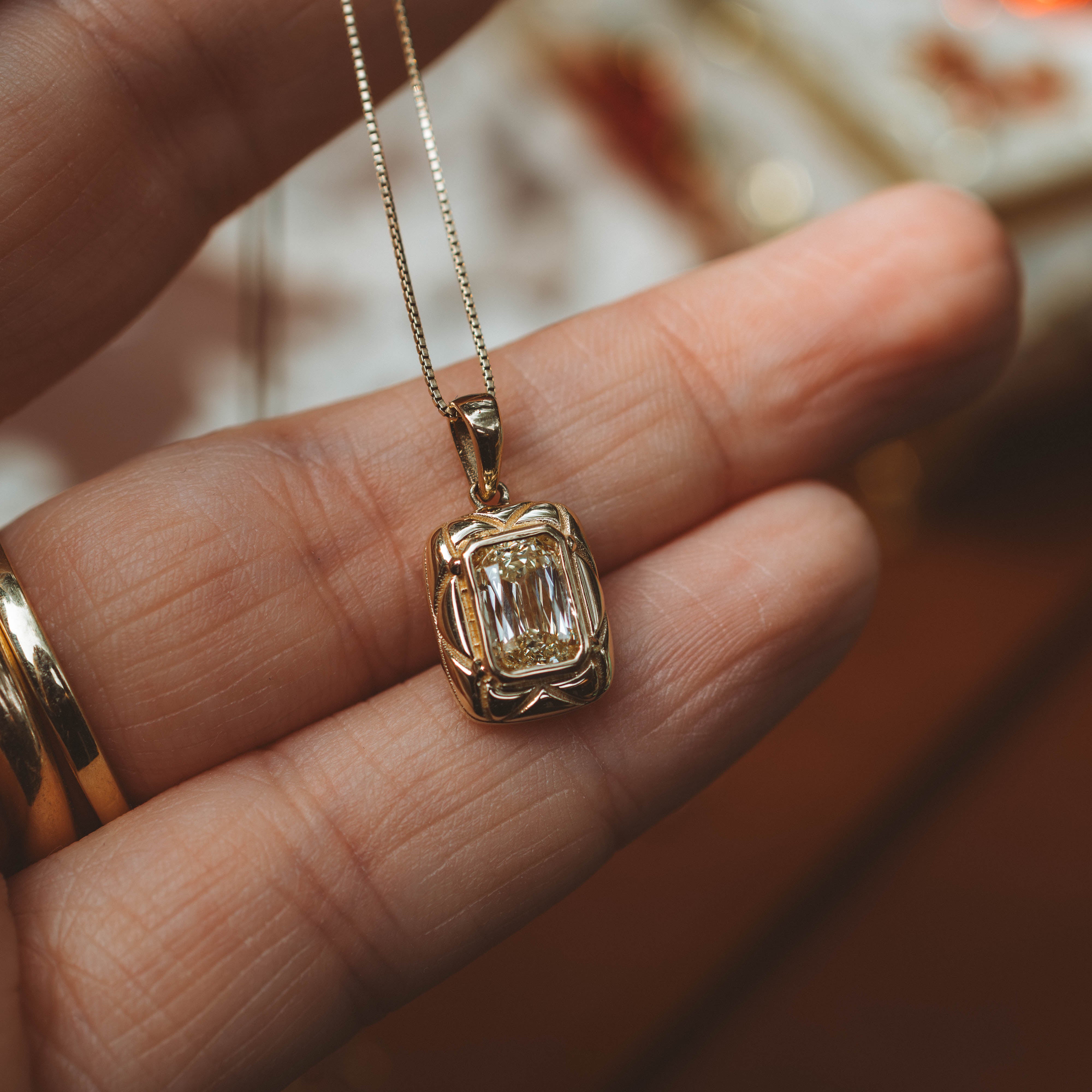 yellow gold pendant on chain held in hand