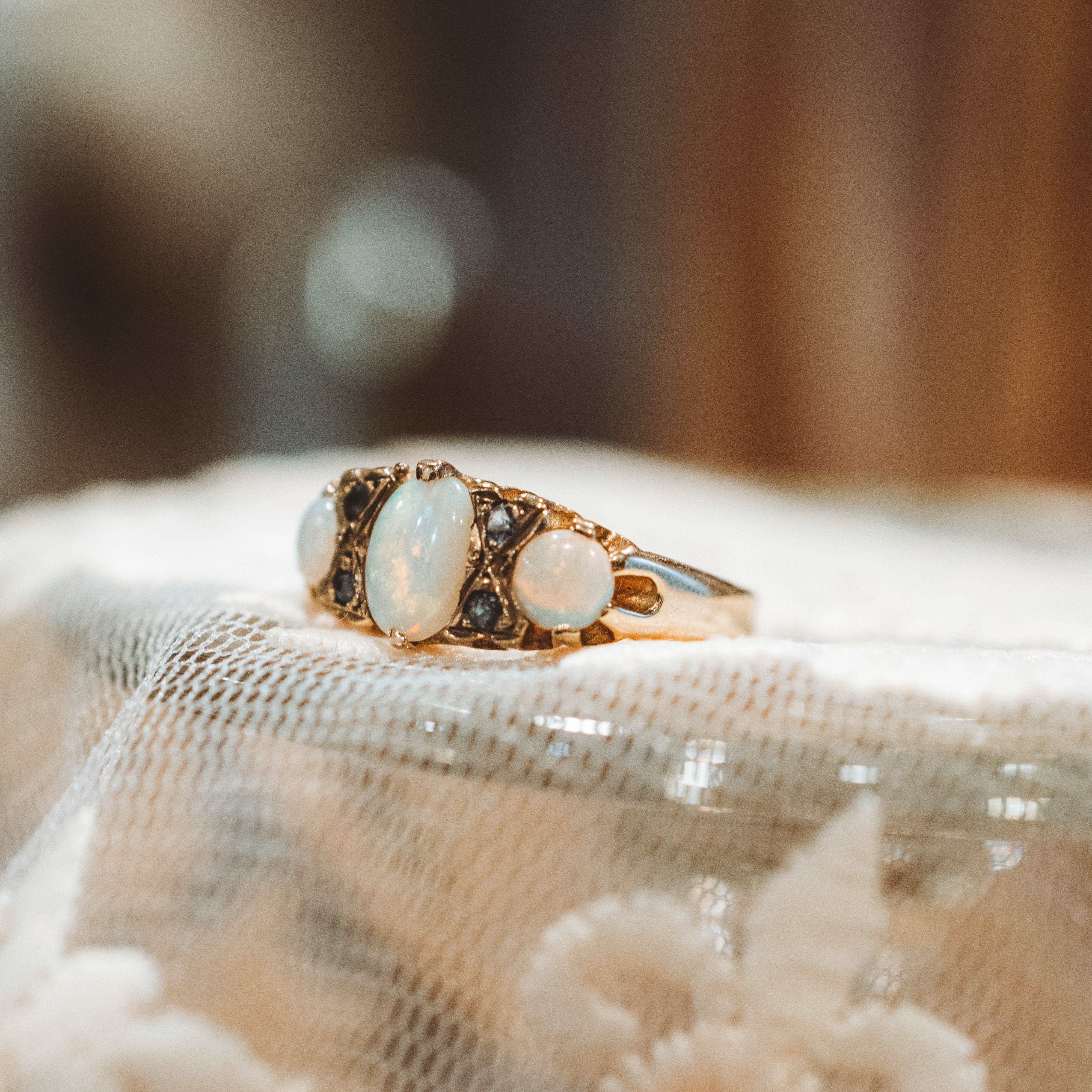 vintage Gold ring with opals and sapphire on a textured fabric background