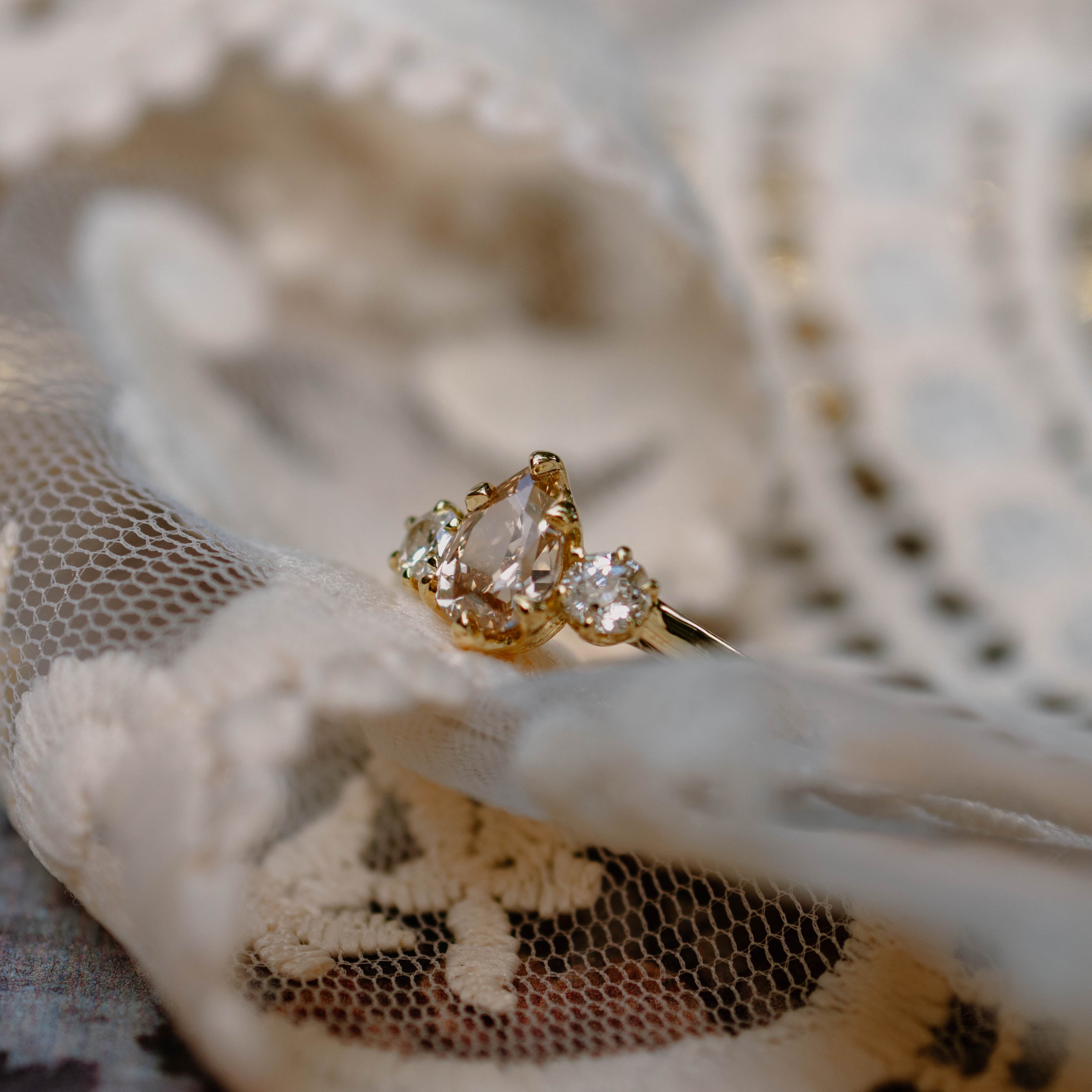 yellow gold three stone champagne engagement ring on lace surface