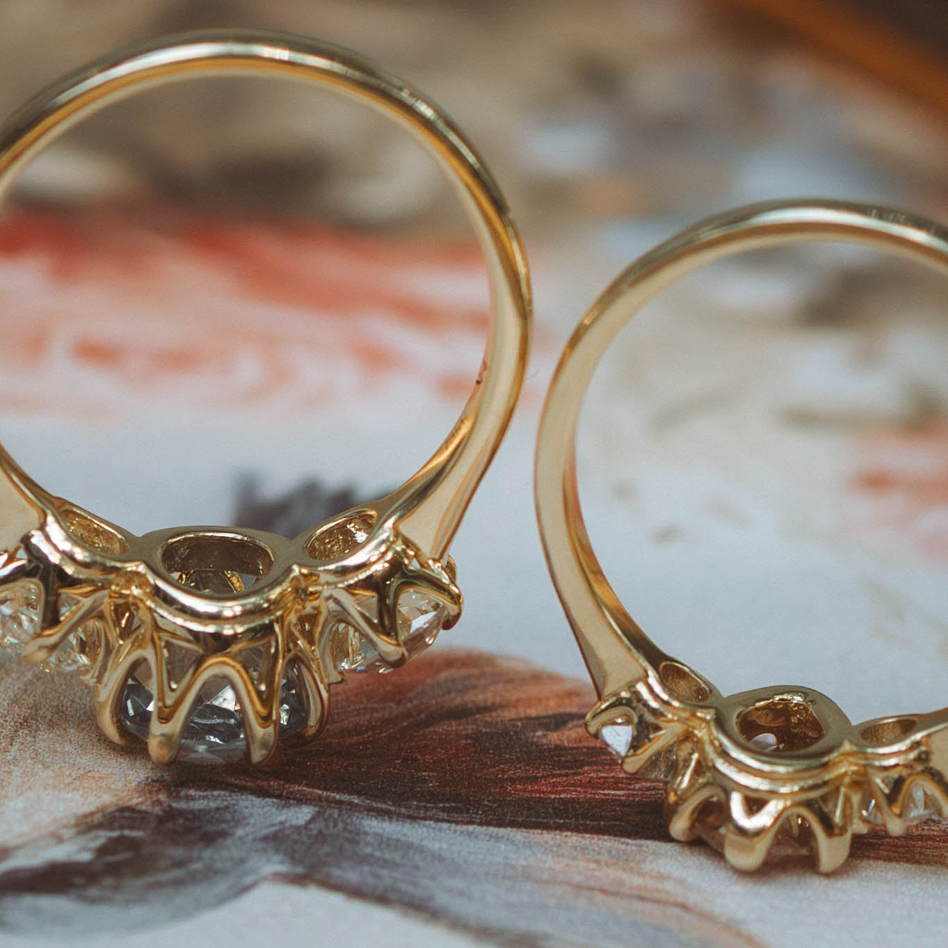 profile baskets of yellow gold trilogy rings on painted background