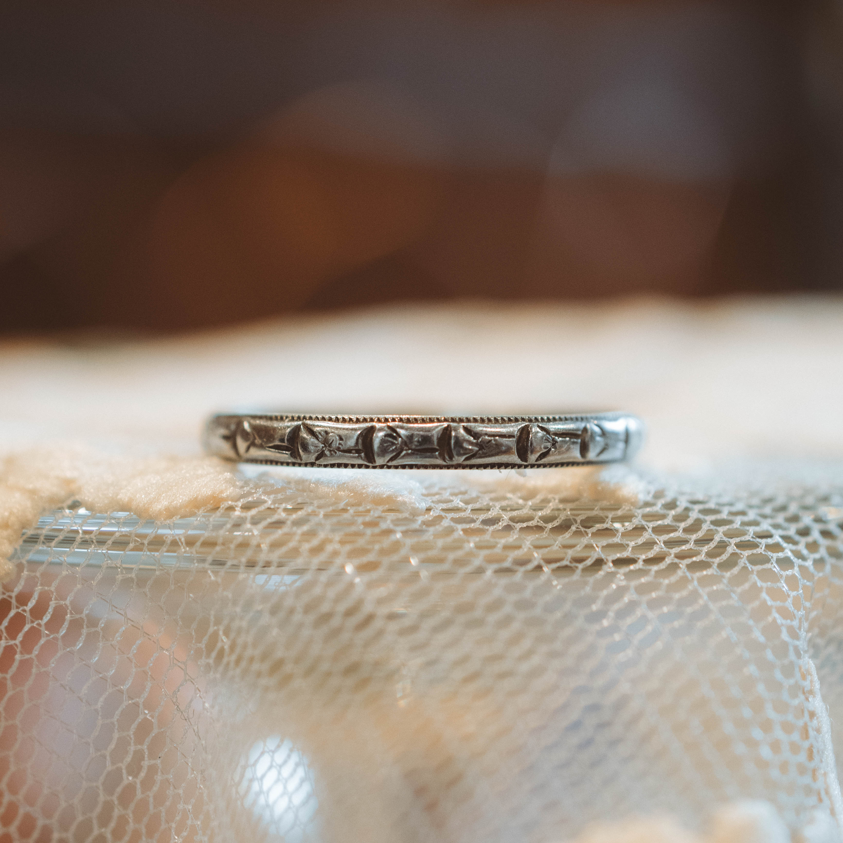 white gold ring with intricate design on a textured surface