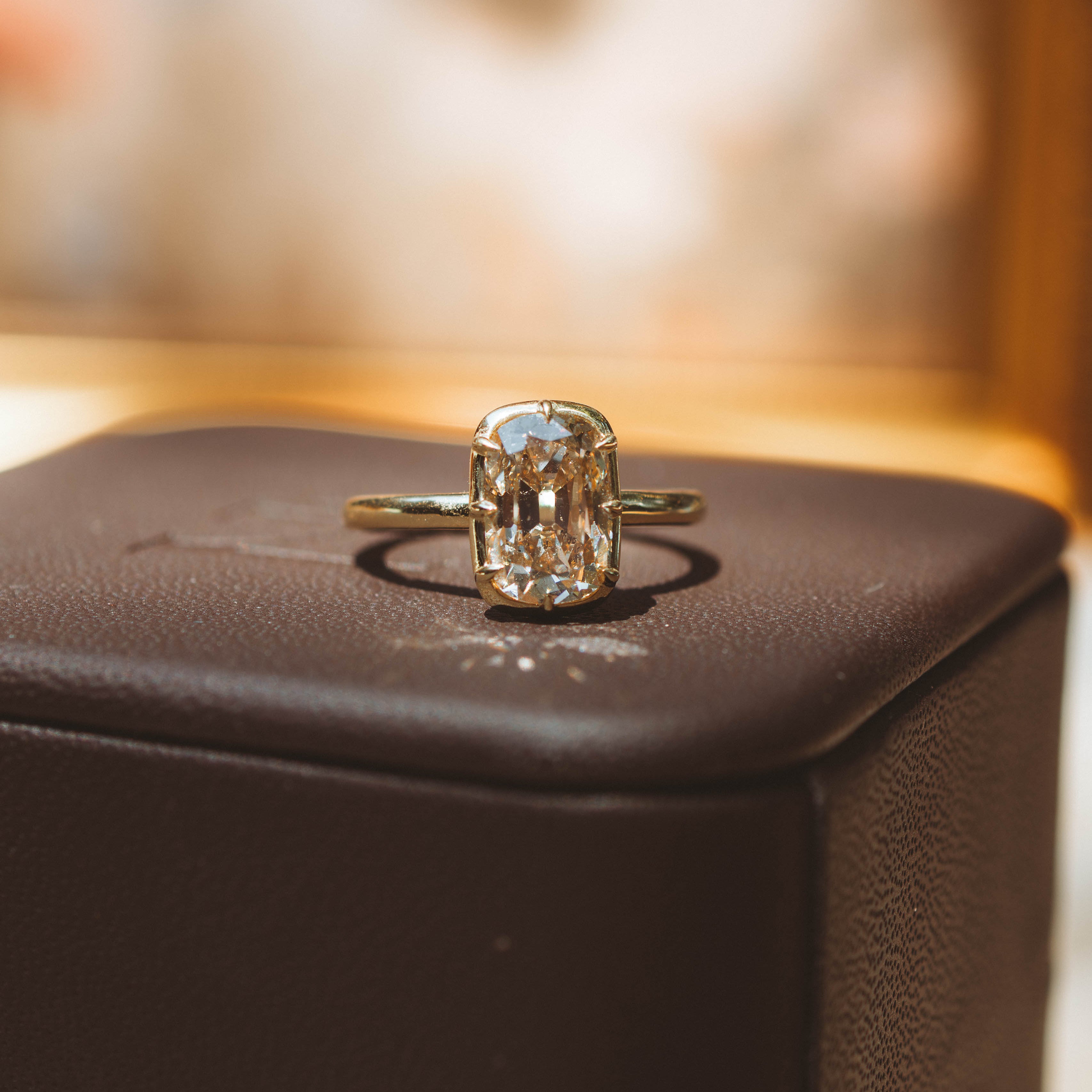 Gold ring with a diamond on a brown jewelry box
