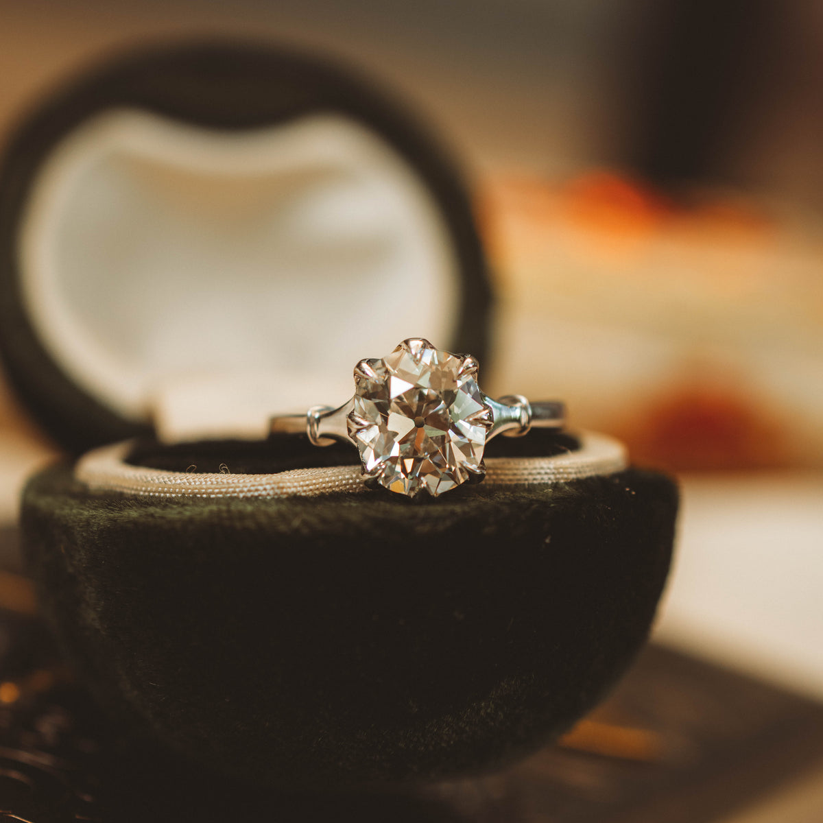 A diamond engagement ring with a silver-toned band and small side stones, displayed in an open black velvet ring box.