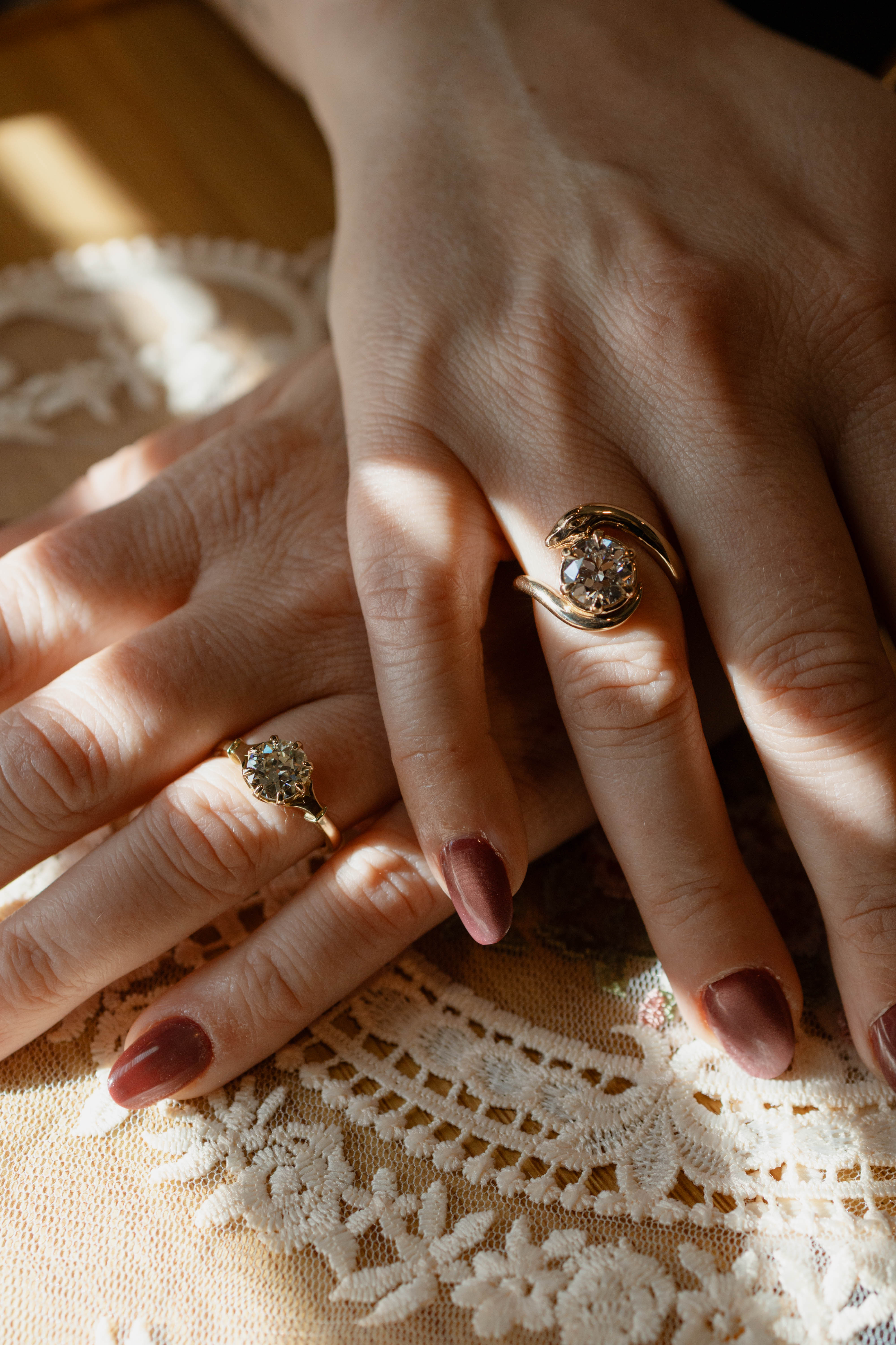 Close-up of two hands with yellow gold diamond rings on a lace fabric