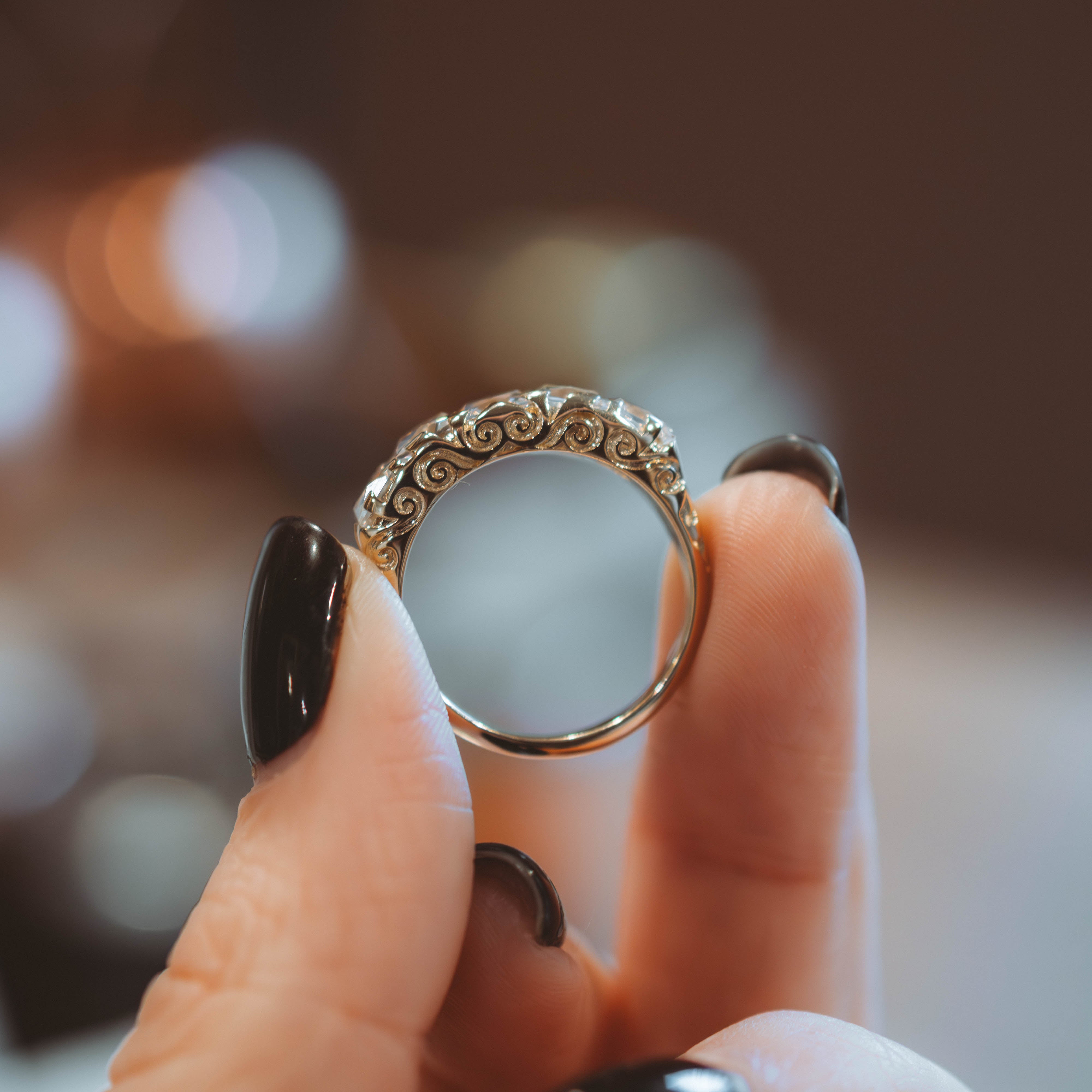 Decorative ring held between fingers with a blurred background