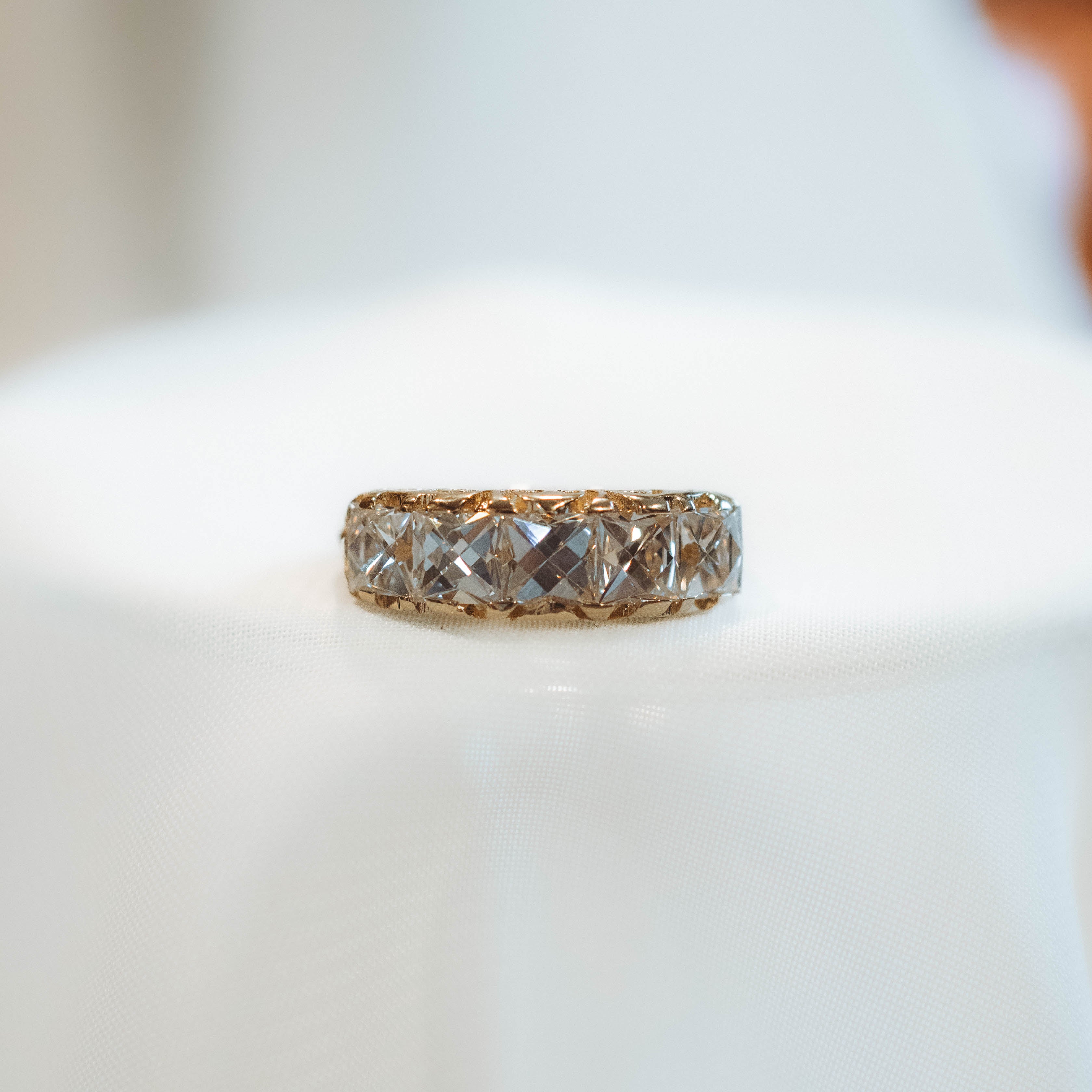 vintage style Gold ring with french cut diamonds on a textured fabric background