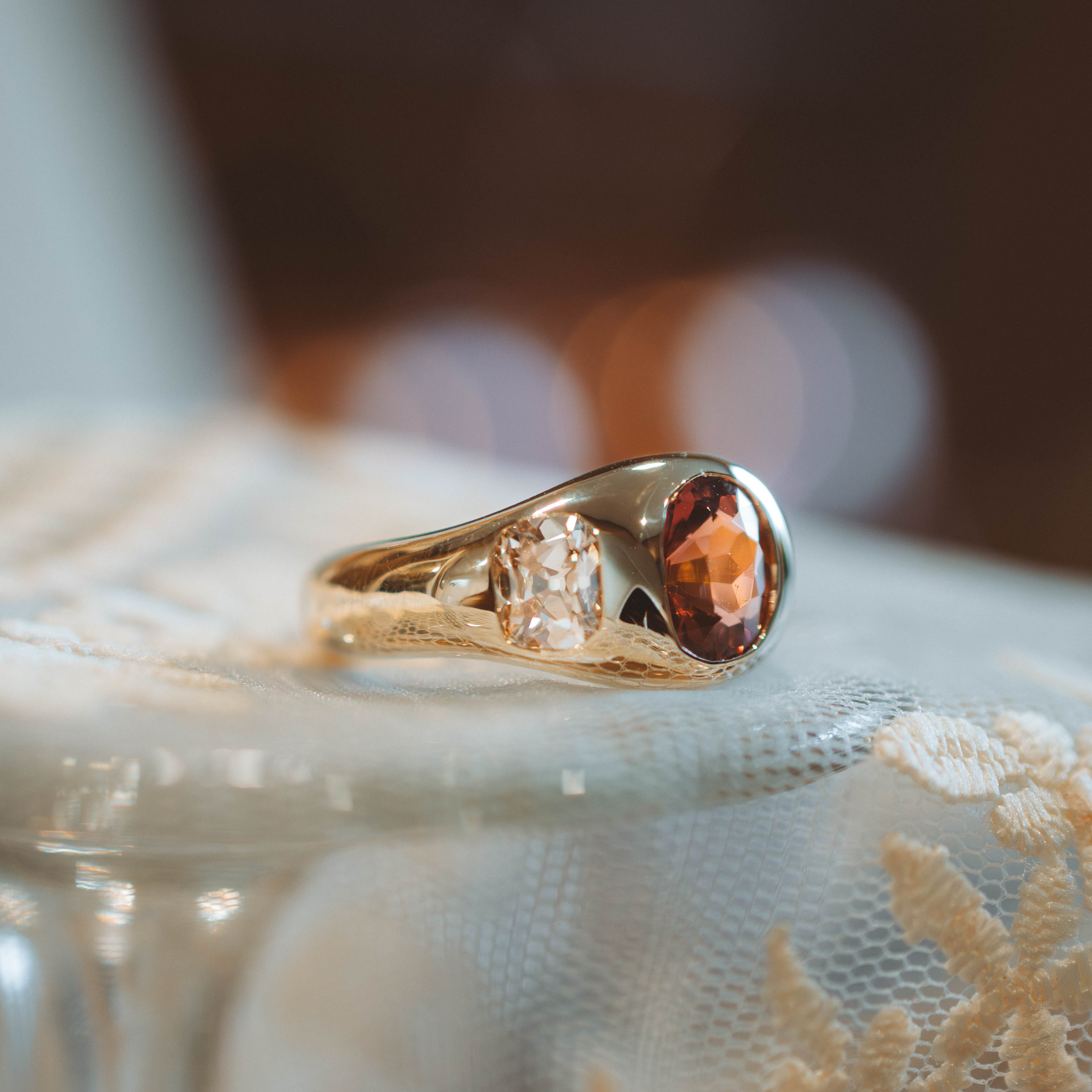 Gold ring with tourmaline gemstone and diamonds on a textured surface