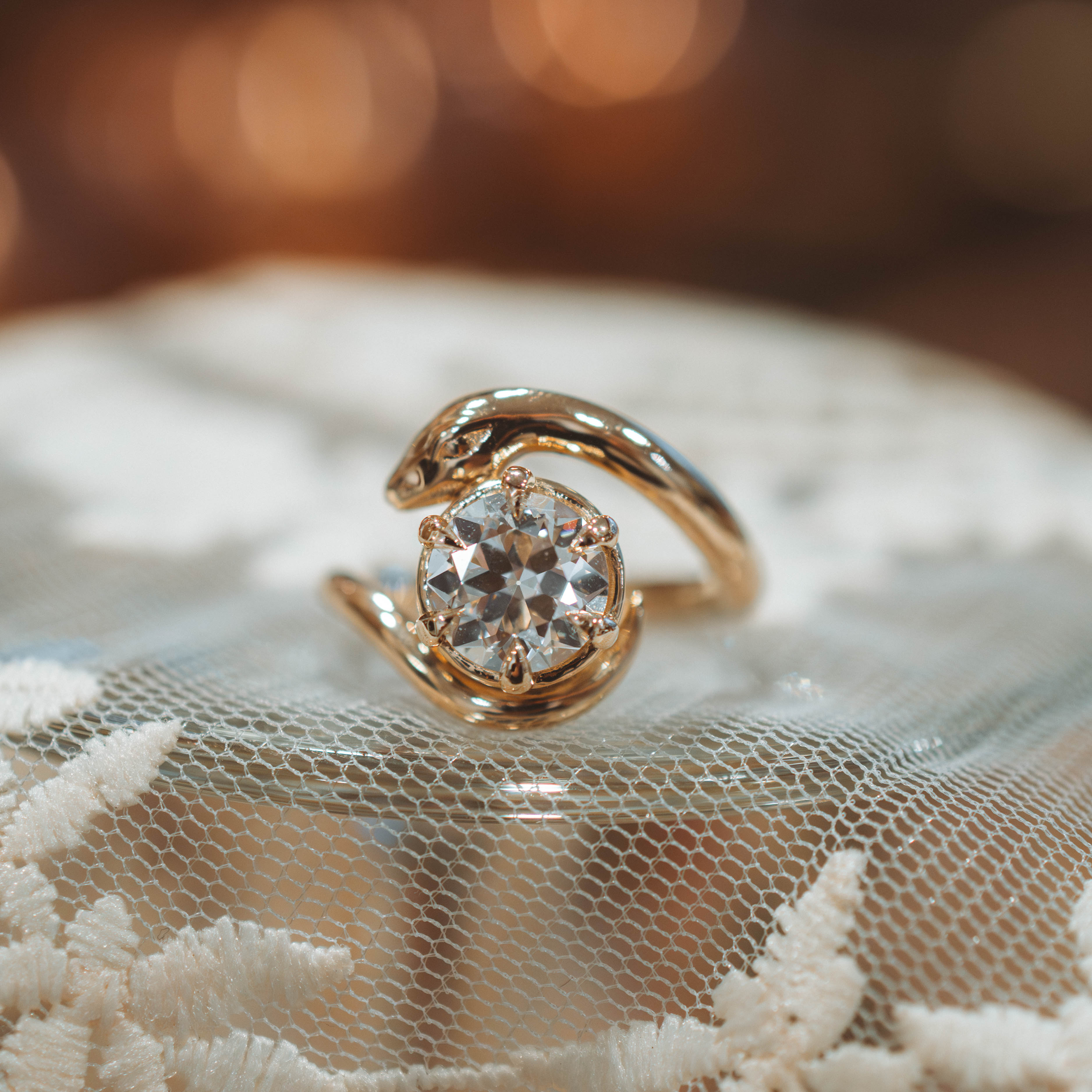 Diamond serpent victorian inspired Gold ring with a diamond on a lace fabric background