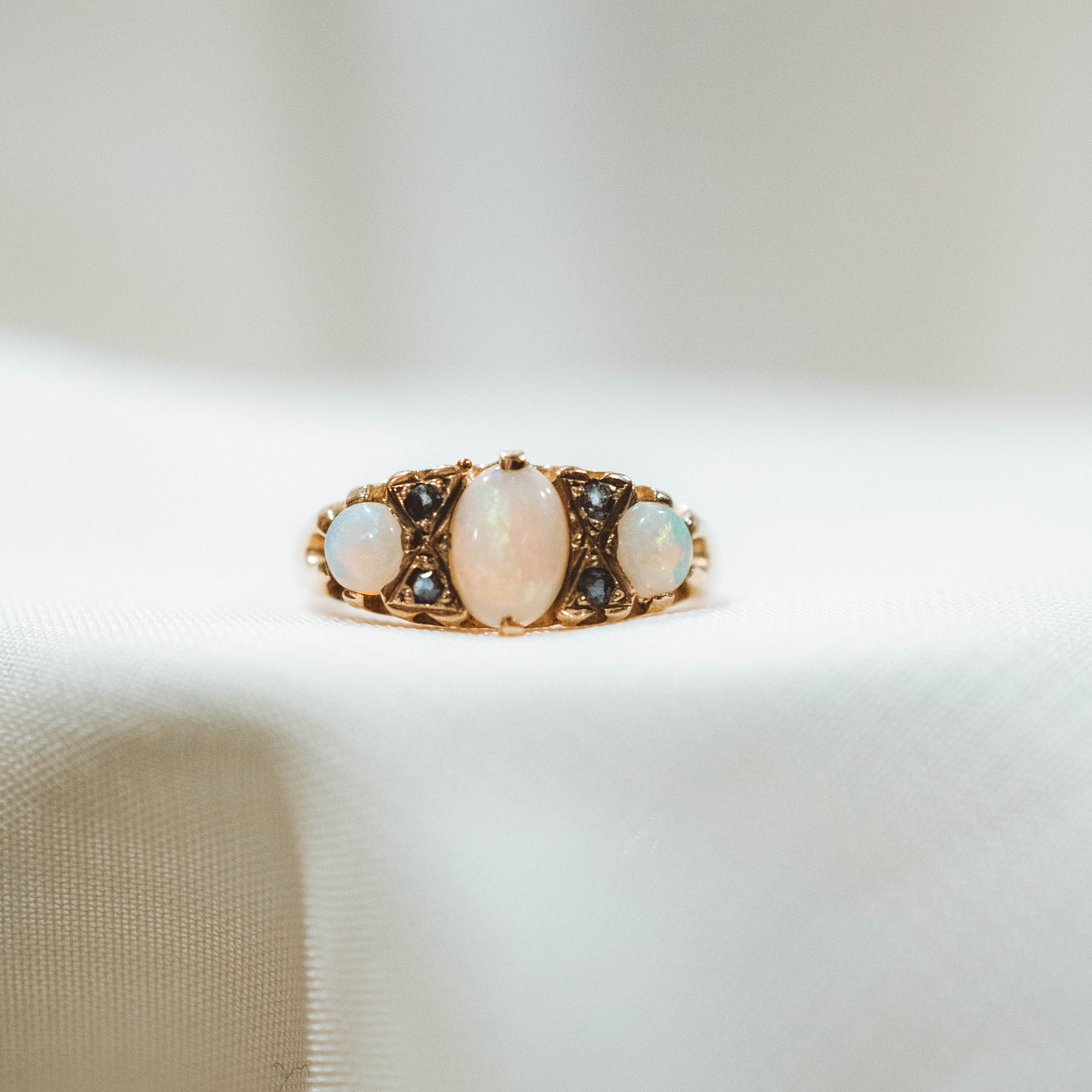 vintage Gold ring with three opal stones and sapphires on a neutral background
