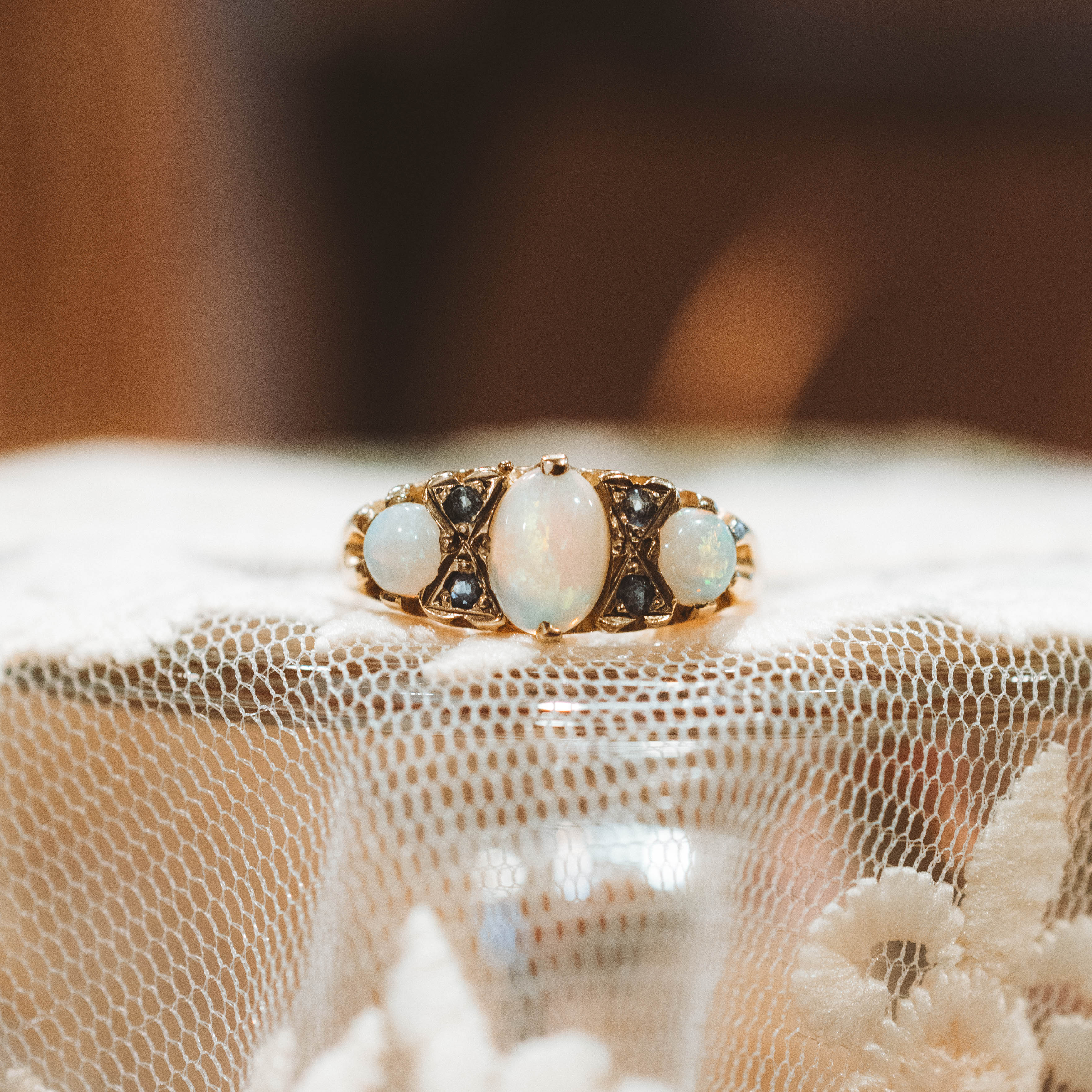 vintage gold ring with opal and sapphire stones on a textured fabric background