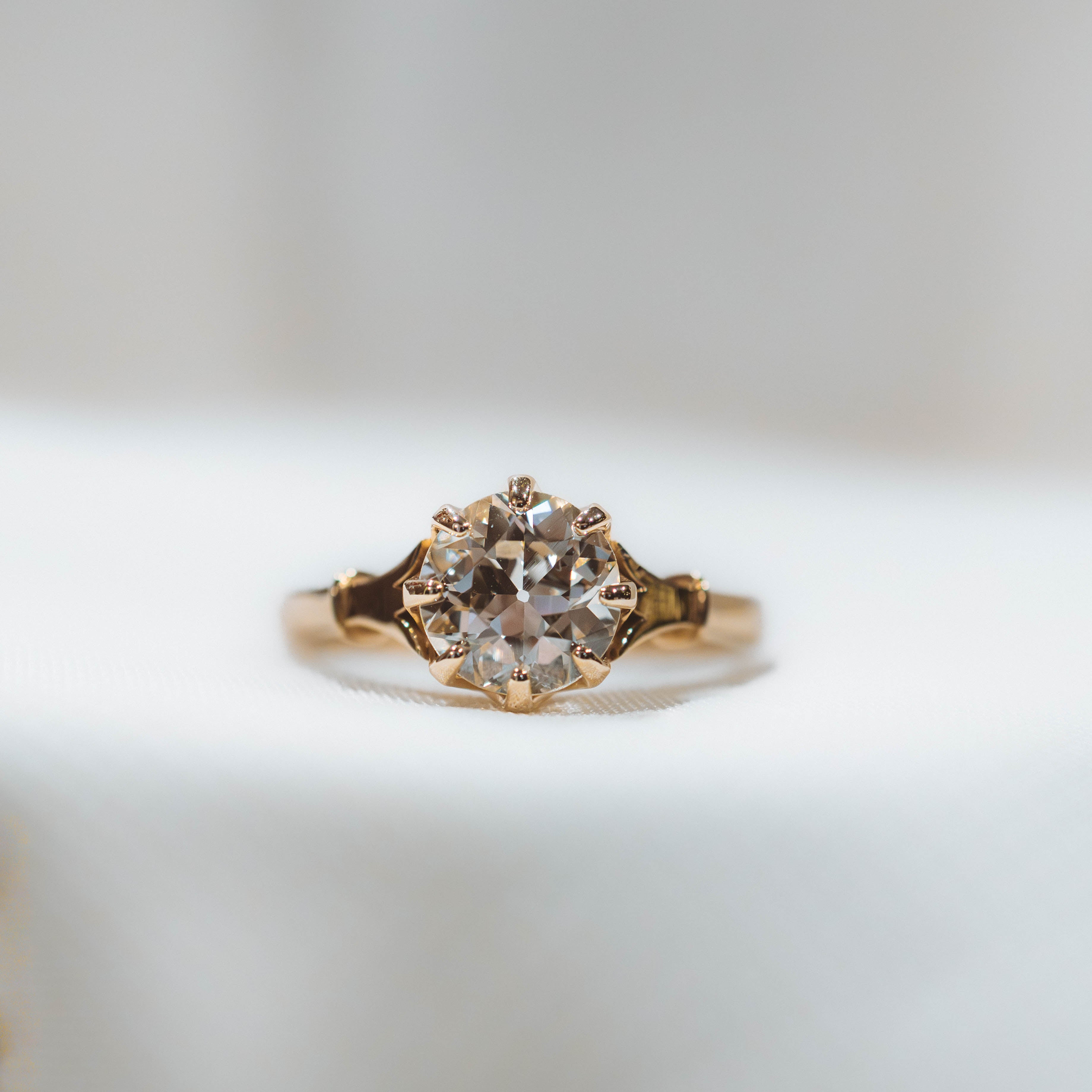 Gold engagement ring with antique diamond on a light gray background