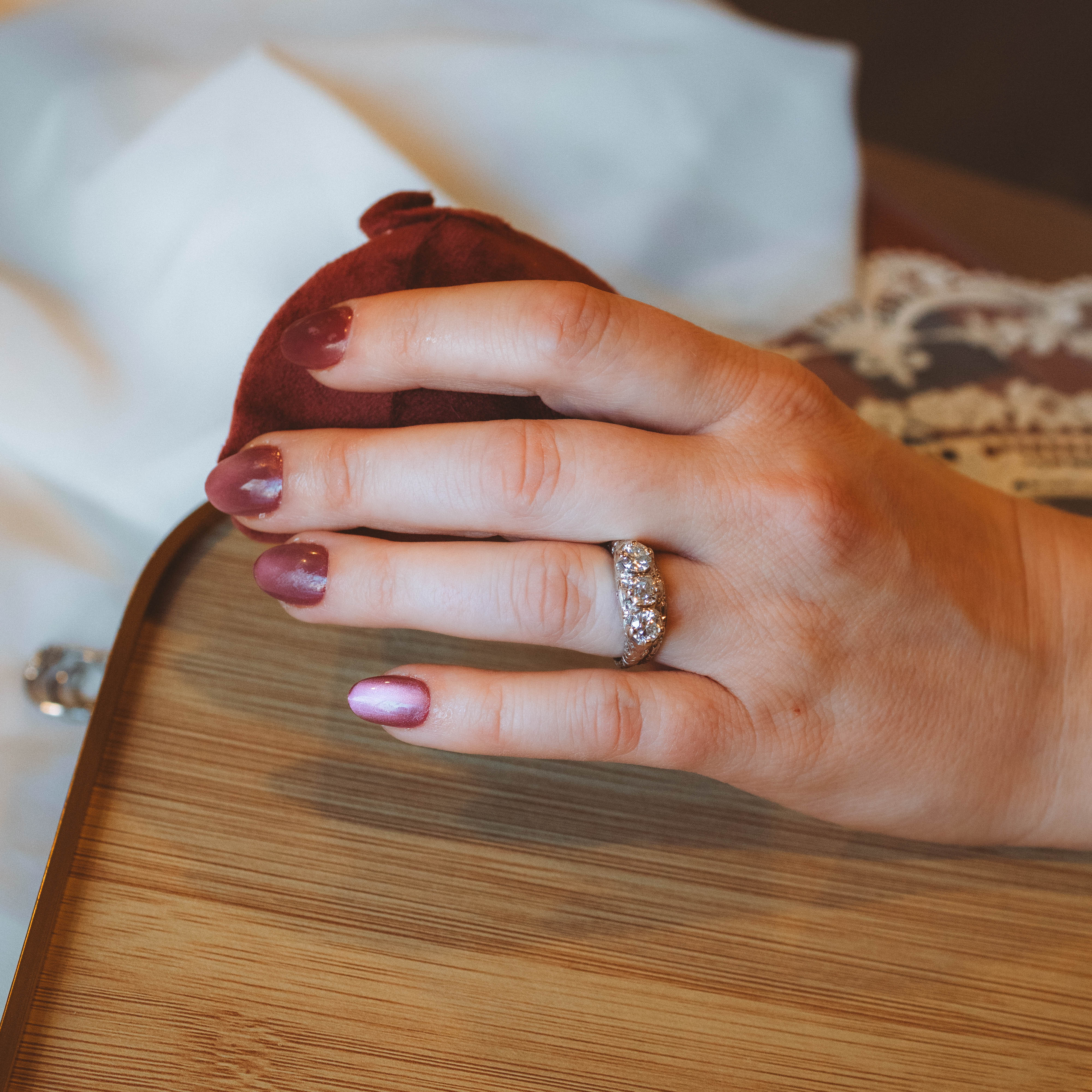 Hand with an art deco trilogy ring on a wooden surface