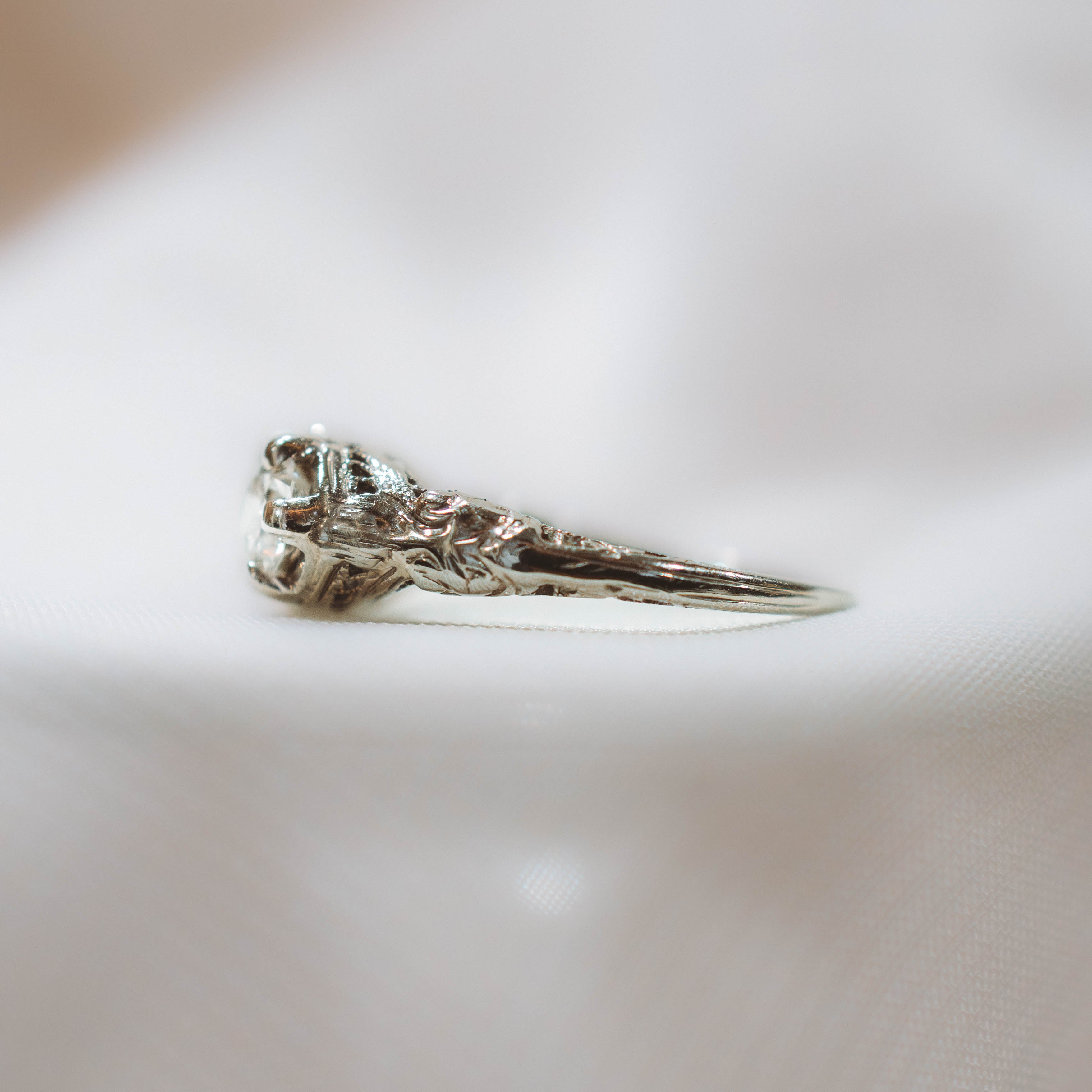 white gold ring with carved detailing on white surface