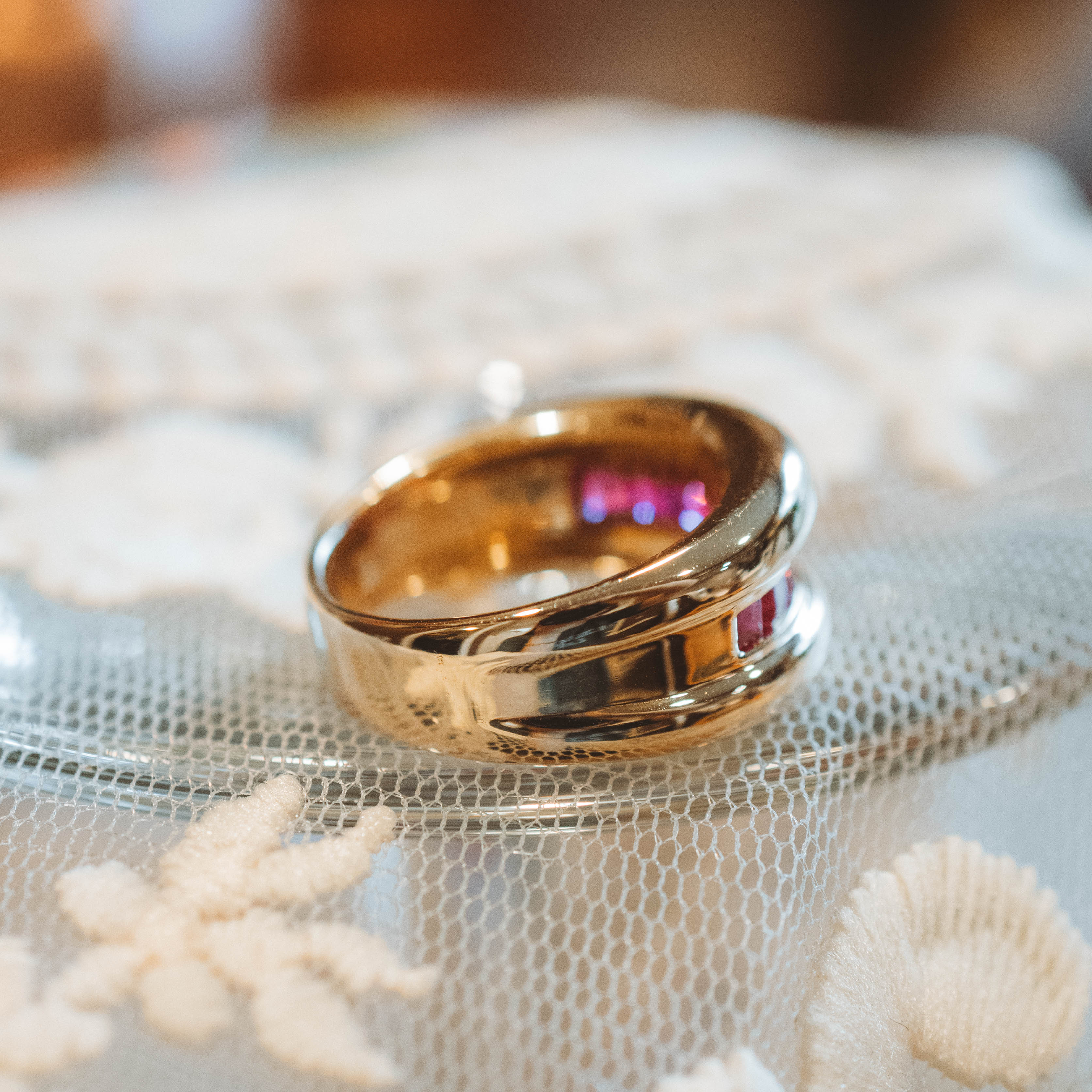 chunky Gold ring with a red ruby gemstone on a white fabric background