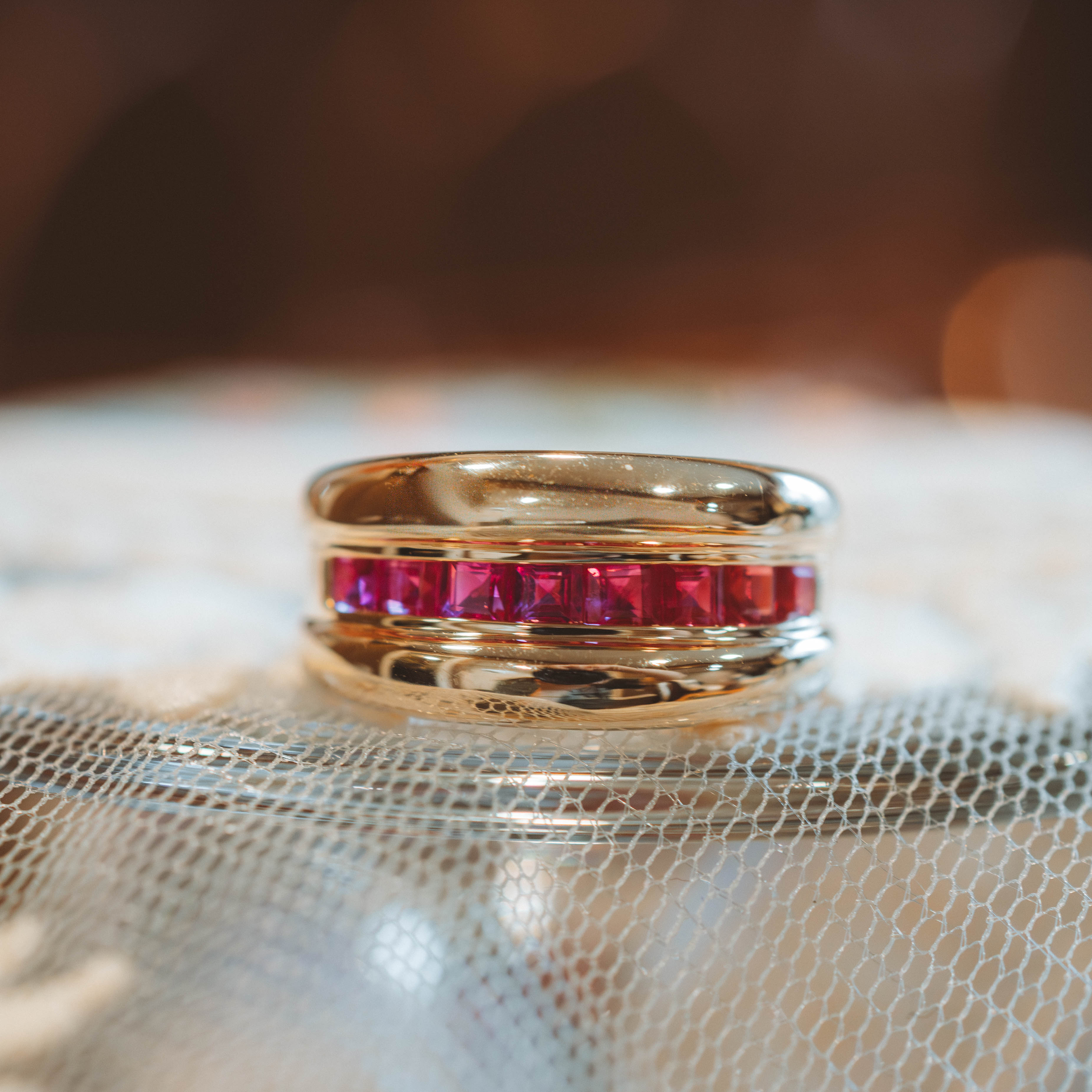 Gold ring with red ruby gemstones on a textured surface