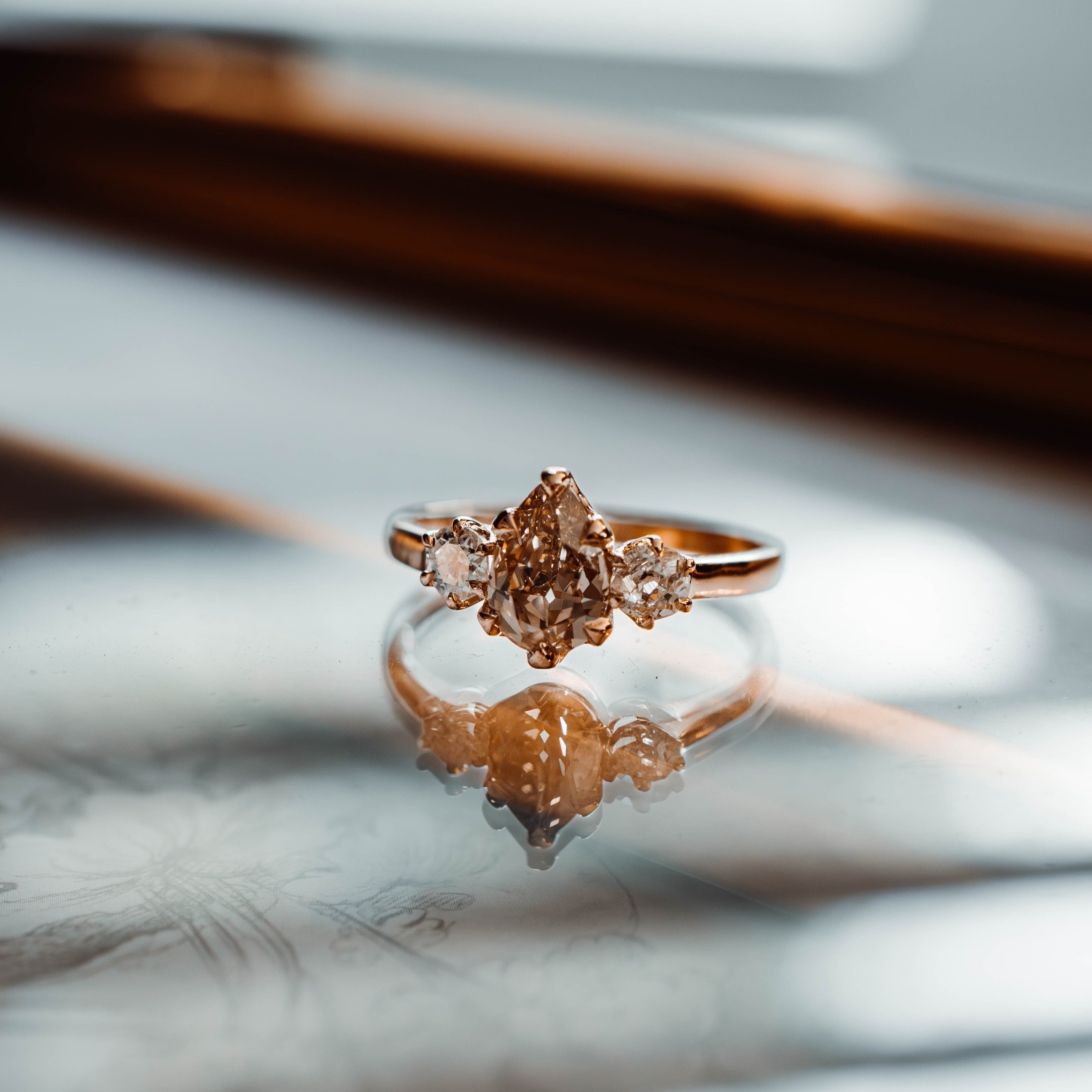 yellow gold ring with 3 diamonds on a reflective surface