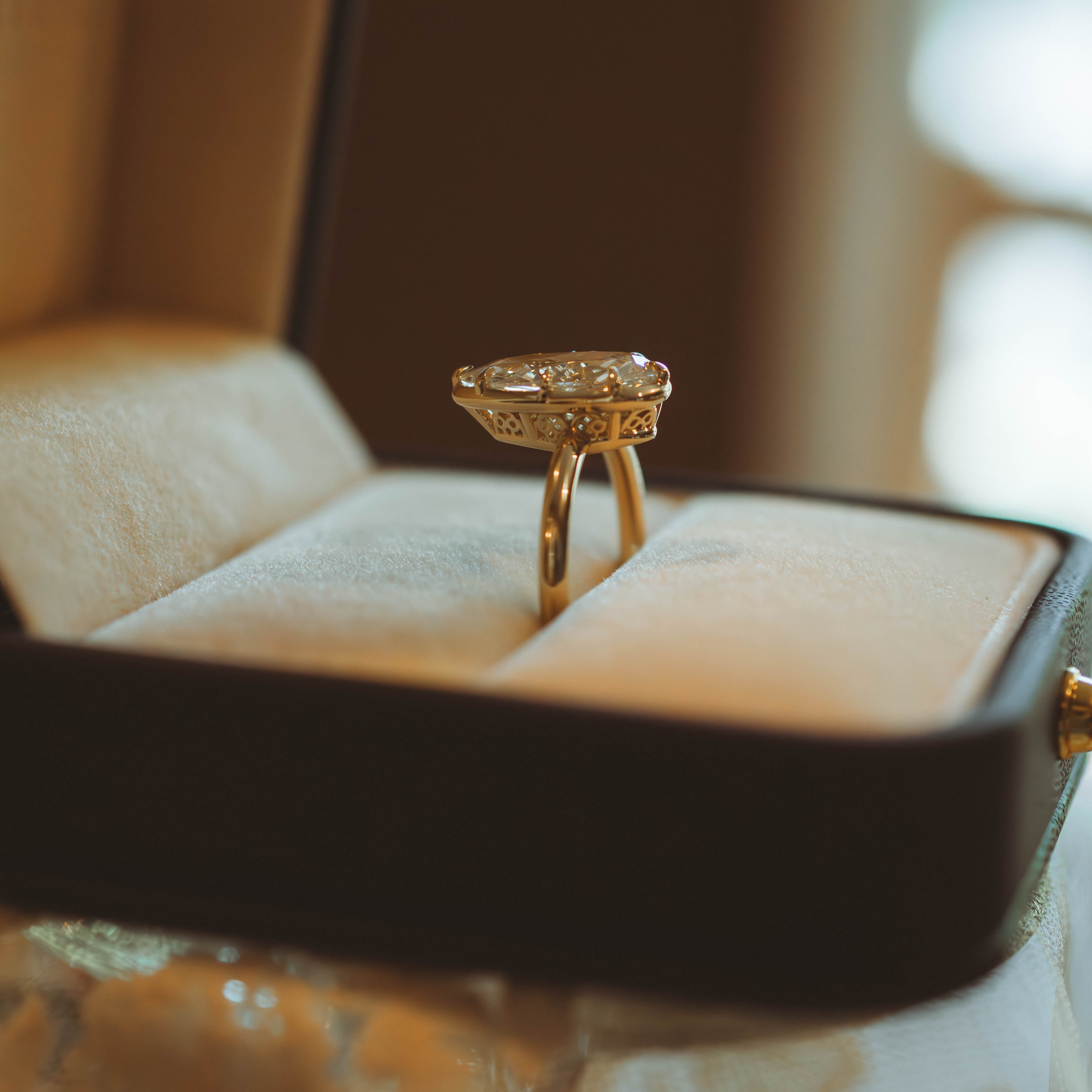 Gold ring with intricate design on a cushioned surface