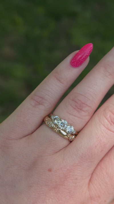 vintage diamond trilogy modeled on hand with wedding band