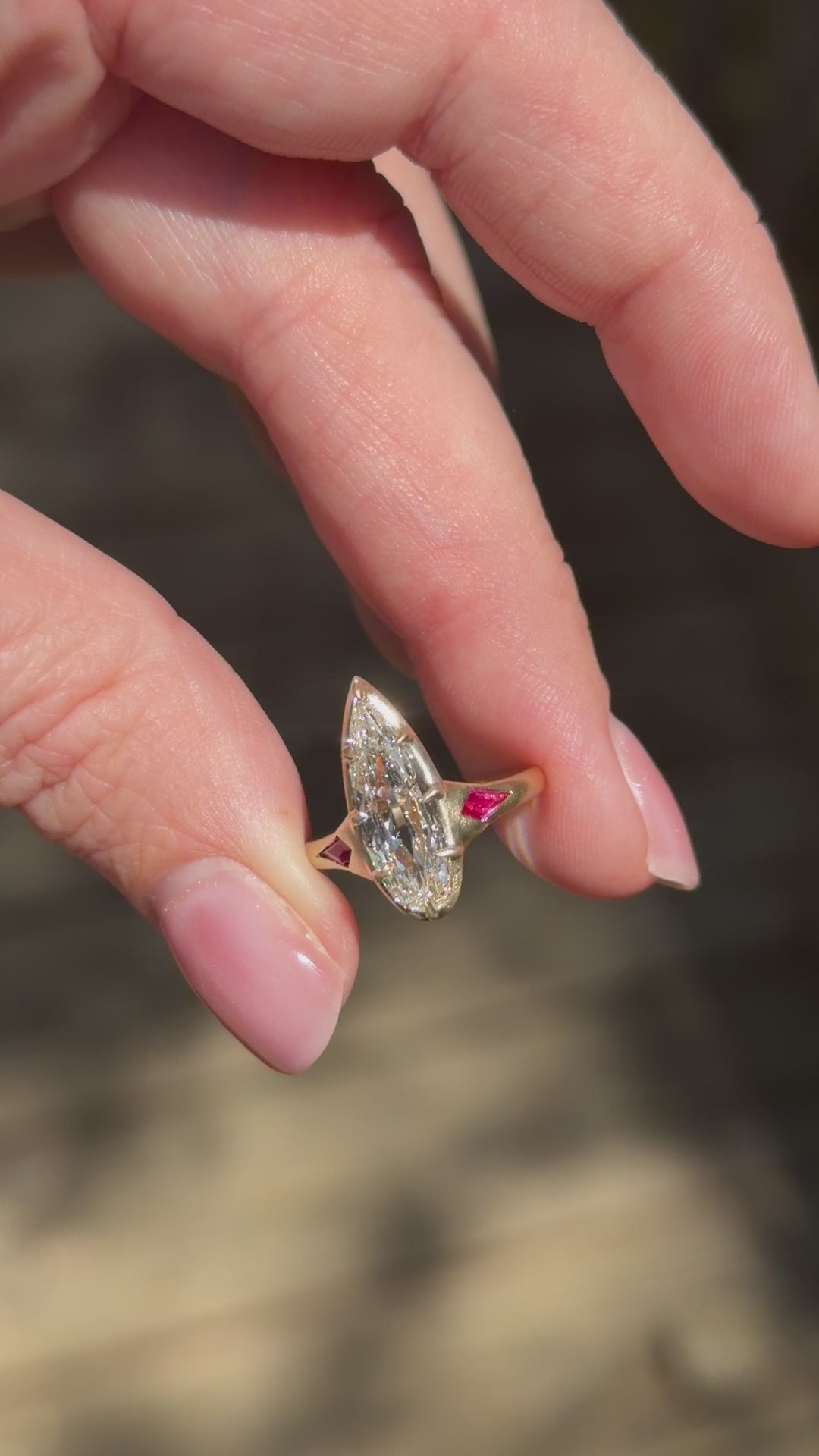 hand turning elongated pear engagement ring set in satin finish yellow fold with ruby kite accents 