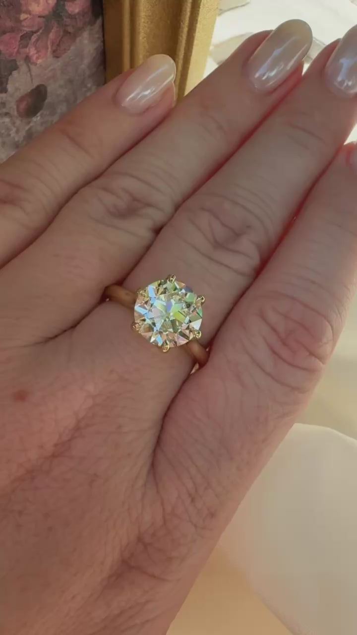 large round old european diamond solitaire ring  yellow gold worn on hand in sunlight