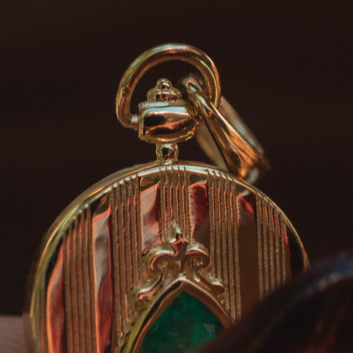 yellow gold pocketwatch style pendant medallion with emerald green gemstone macro show of top gold casted crown