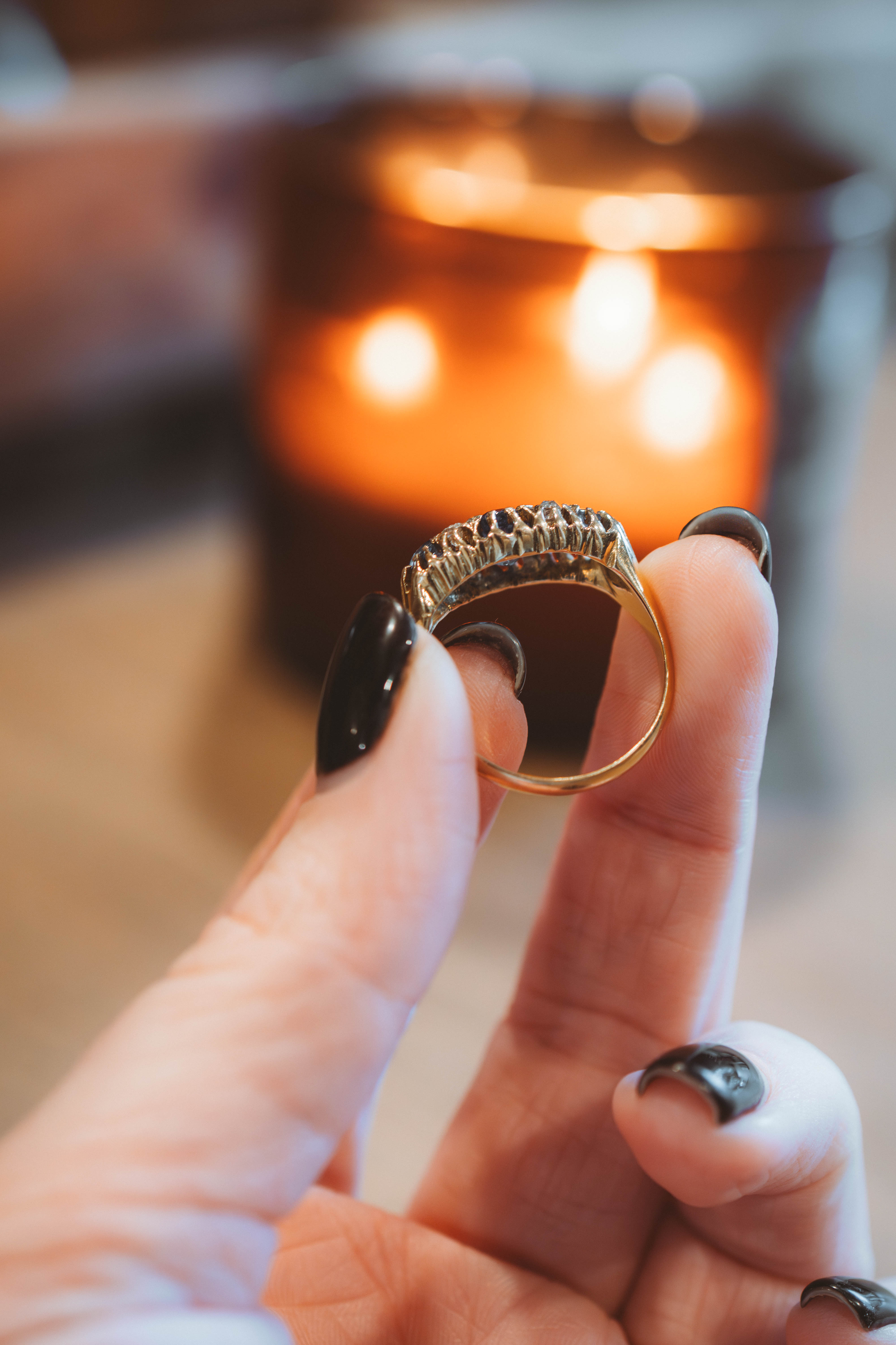 antique Gold and sapphire  ring held between fingers with a blurred background